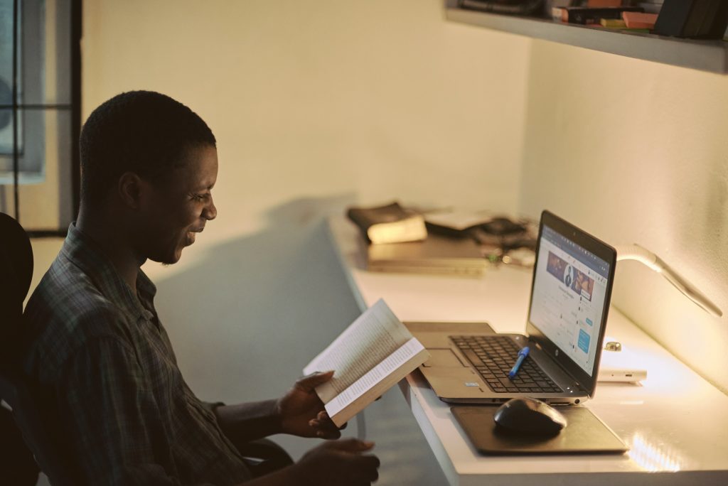 Man sitting at a desk with an open book and laptop