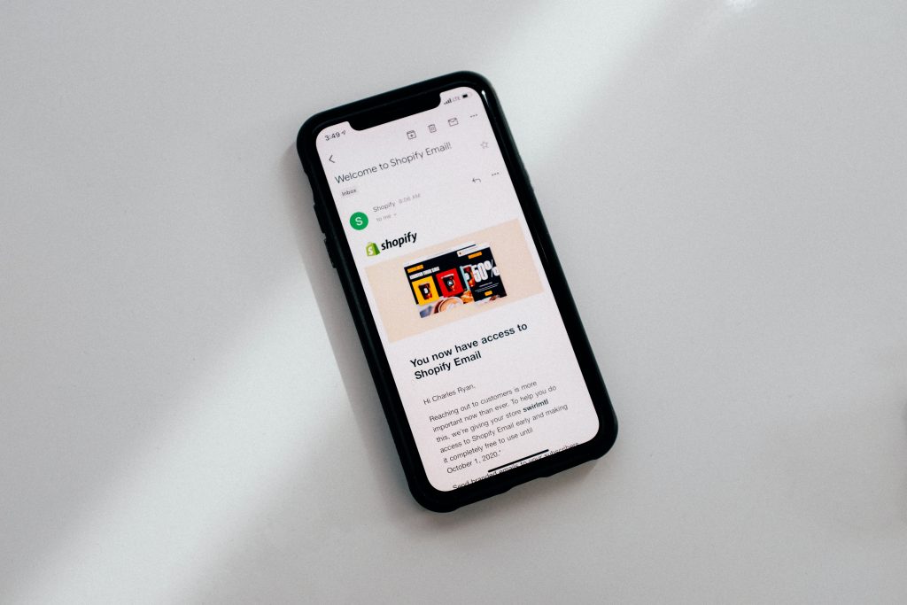 Black iPhone with Shopify confirmation email on screen